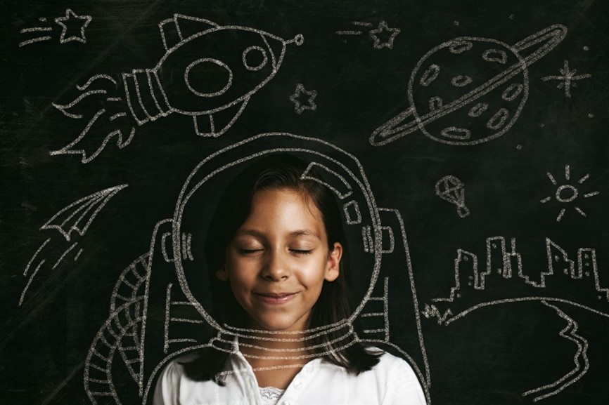 A girl with eyes closed in front of a blackboard filled with science
